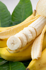 Fresh sliced banana arranged beautifully with green leaves on white background © kei u