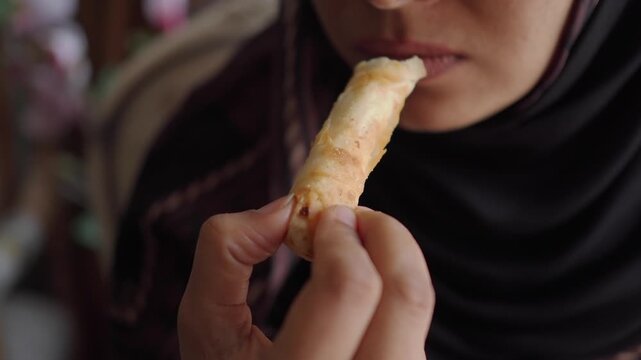 Woman in Hijab Eating a Crispy Spring Roll