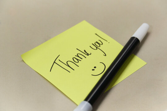 Handwritten Thank You text and smiley face on yellow sticky note with marker pen