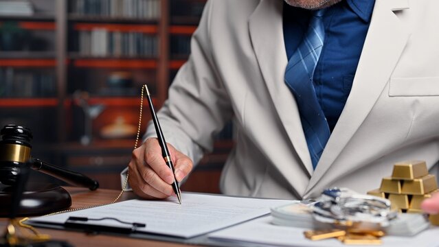 Lawyer signs legal contract beside money, corporate lawyer approving official contract document near legal gavel, experienced lawyer handling financial corruption investigation.