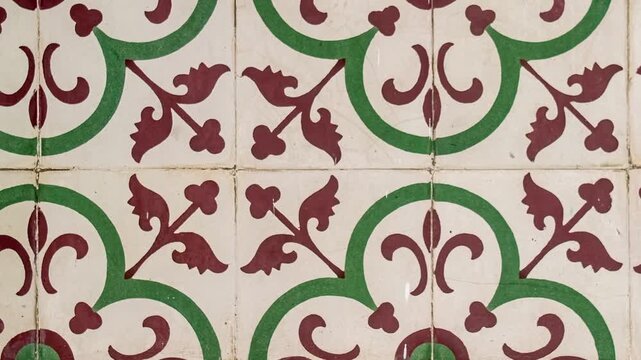 Seamless rotating loop of vintage ceramic floor tiles featuring traditional green and red floral patterns on a white glazed surface background.
