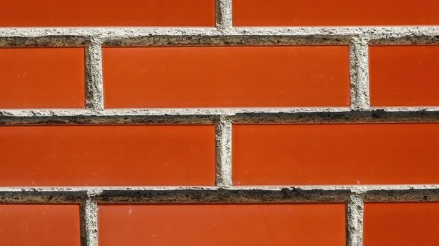 Seamless rotating loop of a glossy orange ceramic brick wall texture with textured cement mortar lines and clean modern tile patterns.