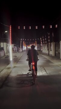 Cyclist Riding Down Illuminated Street at Night
