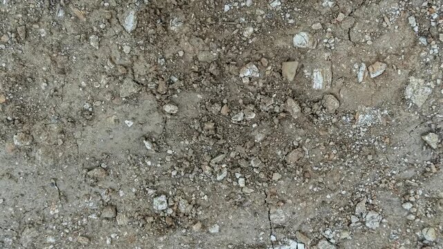 Seamless rotating loop of dry cracked earth ground texture with rough soil, stone pebbles, and natural earthy terrain patterns.