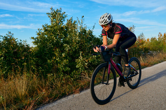 Female Cyclist Riding Road Bike Outdoors on Sunny Day Training for Triathlon or Fitness