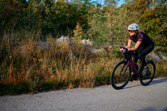 Female Cyclist Riding A Road Bike On Countryside Path During Autumn Training Ride