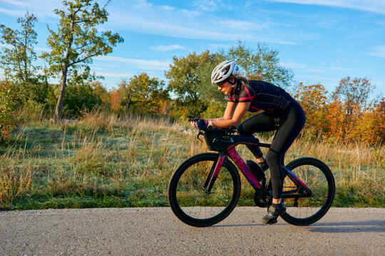 Female Cyclist Training on Road Bike in Autumn Countryside for Fitness and Triathlon Preparation
