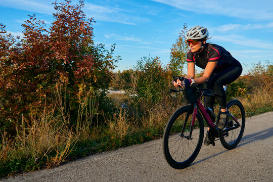 Female Cyclist Training on a Road Bike Along Autumn Trail During Outdoor Fitness Ride