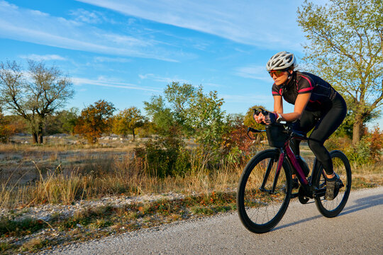 Female Cyclist Training On Road Bike In Countryside During Sunny Outdoor Fitness Ride