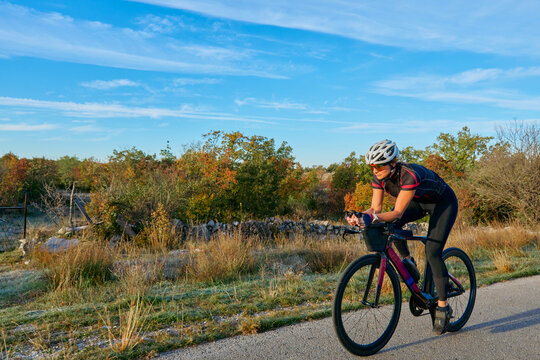Female Cyclist Training on Country Road at Sunrise for Outdoor Fitness and Endurance