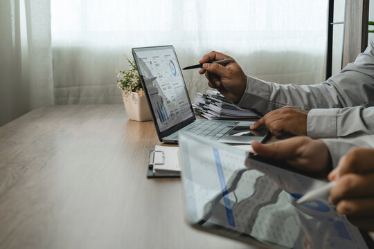 two businessmen discussing accounting data on laptop and tablet during financial consultation, reviewing dashboard charts and reports for business planning.