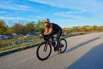 Naklejka premium Female Cyclist Training On Aero Road Bike During Sunny Countryside Ride