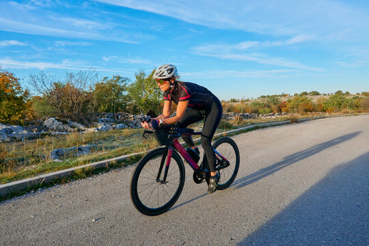 Female Cyclist Training On Aero Road Bike During Sunny Countryside Ride