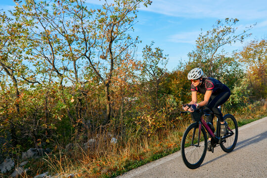 Female Cyclist Training on a Road Bike Through Autumn Countryside for Fitness and Endurance
