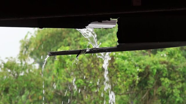 Slow motion of water is flowing from the roof of the house. The rain falling on a roof.