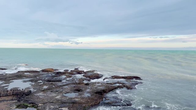 Waves Crashing on Rocky Coastline at Sunset 
