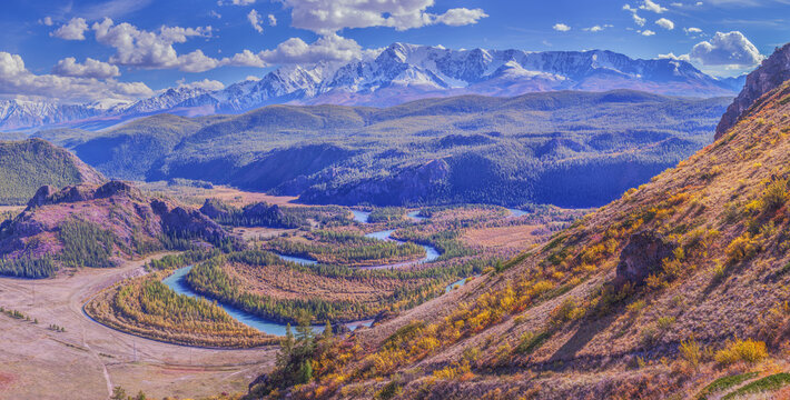 Mountain autumn landscape, river meanders in the valley, snow-capped peaks