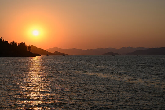 Shining golden sunset over the Mediterranean Sea with silhouettes of mountains on the horizon