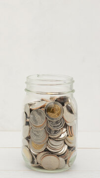 Glass jar full of Thai baht coins. Business and finance concept. Vertical Photography.