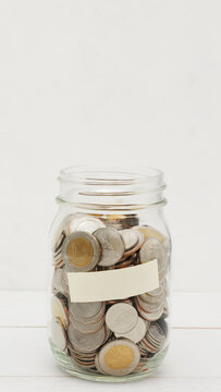Glass jar full of Thai baht coins. Business and finance concept. Vertical Photography.