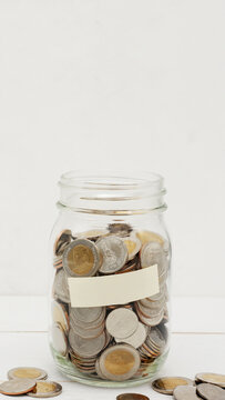 Glass jar full of Thai baht coins. Business and finance concept. Vertical Photography.