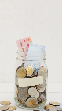 Glass jar full of Thai baht coins. Business and finance concept. Vertical Photography.