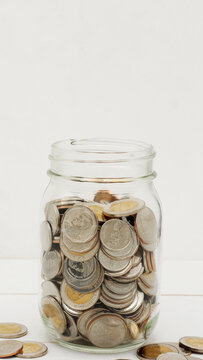 Glass jar full of Thai baht coins. Business and finance concept. Vertical Photography.