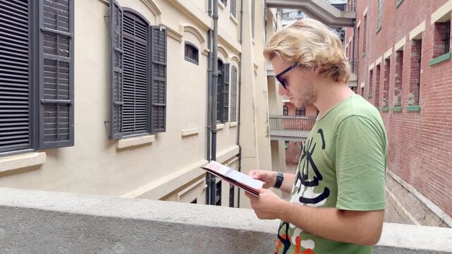 HONG KONG, CHINA &ndash; AUGUST 13, 2026: Young man with route map standing in narrow passageway between colonial buildings at Tai Kwun heritage site, former Victoria Prison.