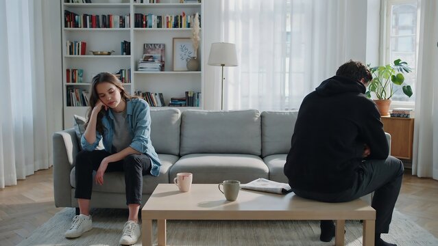 Couple sitting apart on sofa showing relationship conflict and emotional distance at home