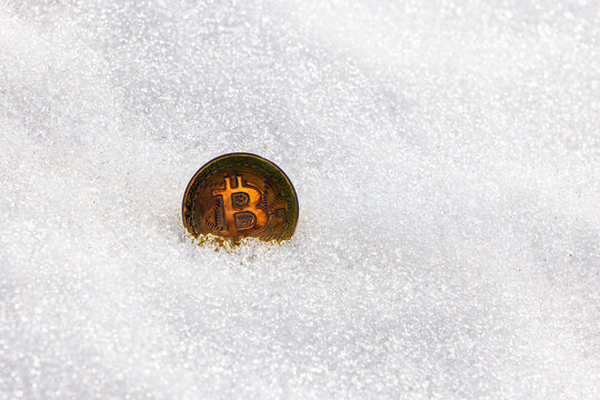 Golden Bitcoin Coin Partially Submerged in Sparkling Snow