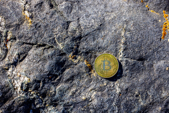 Gold Cryptocurrency Coin on Rough Rock Surface