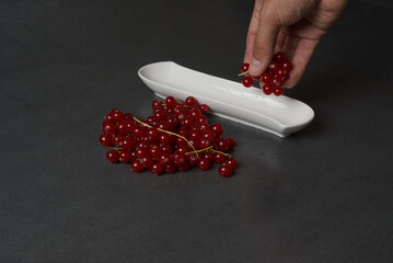 Vibrant red currants rest on a sleek, dark surface © lupiklv