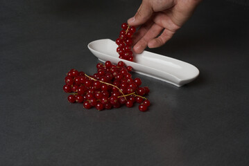 Vibrant red currants rest on a sleek, dark surface © lupiklv
