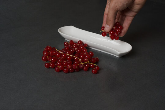 Vibrant red currants rest on a sleek, dark surface