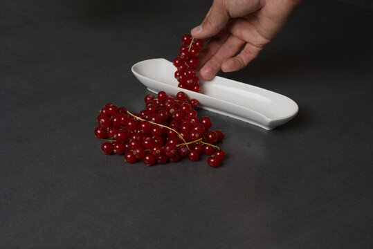Vibrant red currants rest on a sleek, dark surface