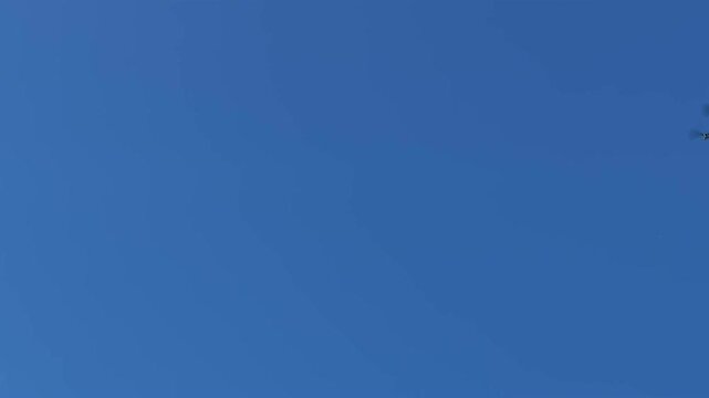 Flying drone with camera hovering in the bright blue sky on a sunny day.