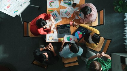 Fototapeta premium Top view of business team working together while talking about financial chart. Close up of skilled marketing team sharing idea and looking at stock market statistic chart at boardroom. Convocation.