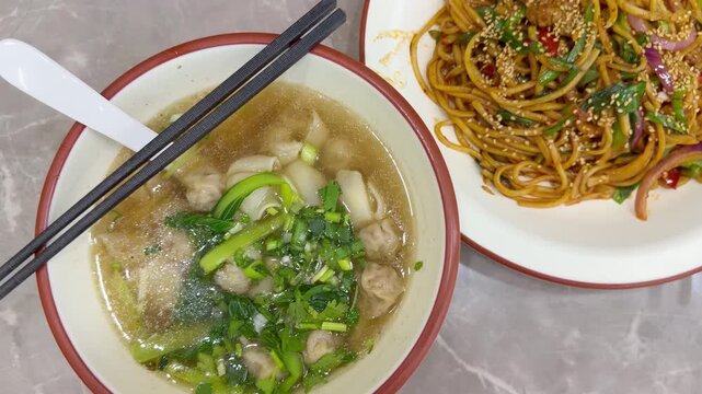 Chinese Restaurant Table with Noodles on Plate and Wonton Soup in Bowl &ndash; Traditional Dumplings and Noodle Dish