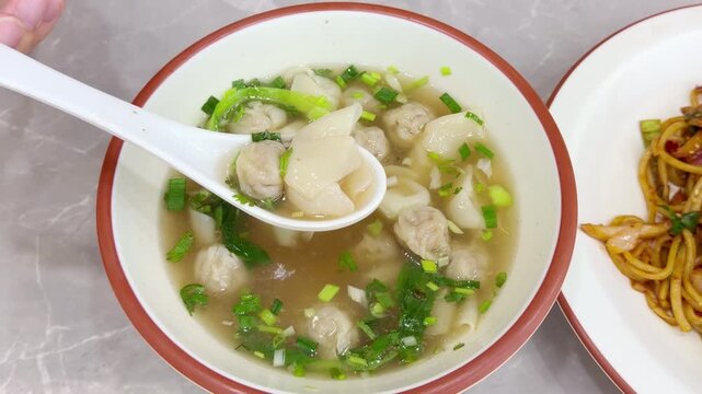 Close Up of Chinese Wontons on Restaurant Table &ndash; Traditional Dumpling Soup with Green Onions