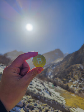 Bitcoin Coin Held Against Mountain Landscape in Kyrgyzstan