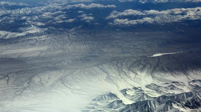 Stunning window seat view of massive snow-covered mountain ranges in Northwest China during a flight. 