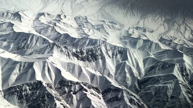 Stunning window seat view of massive snow-covered mountain ranges in Northwest China during a flight. 