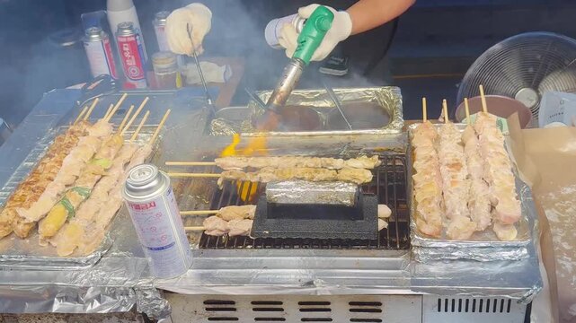 Korean Street Food &ndash; Grilling Skewers and Beef Steak Over Open Flame at Outdoor Market Stall