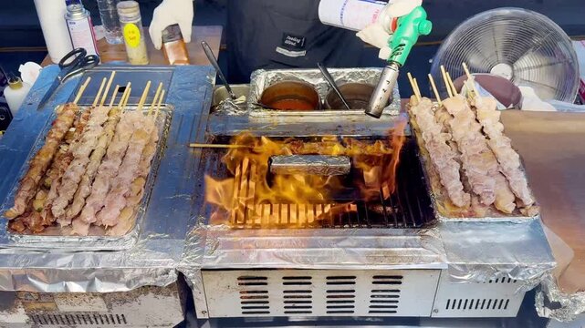 Korean Street Food &ndash; Grilling Skewers and Beef Steak Over Open Flame at Outdoor Market Stall