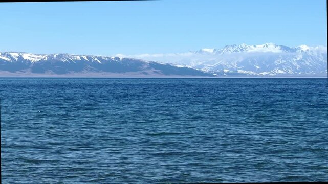 Beautiful scenic view of Sayram Lake with turquoise water and snow-capped Tianshan mountains in Xinjiang, China.