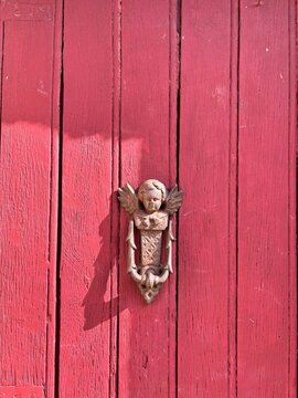 Vintage angel door knocker on a rustic red wooden door