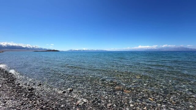 Beautiful scenic view of Sayram Lake with turquoise water and snow-capped Tianshan mountains in Xinjiang, China.