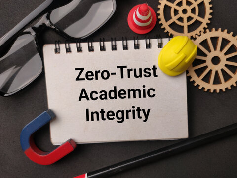 A notepad displaying Zero-Trust Academic Integrity lies near gears, hardhat, cone, magnet, glasses, and pencil on dark gray