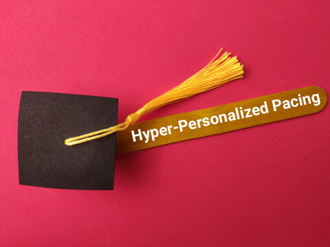 A yellow craft stick labeled Hyper-Personalized Pacing lies under a black graduation cap tassel on red