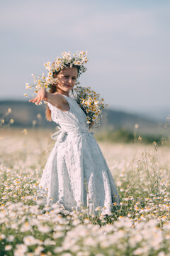Summer playtime featuring a young girl wearing a floral crown in a field of Matricaria chamomilla daisy flowers